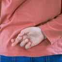 Niña cruzando los dedos detrás de la espalda sobre un fondo claro con espacio para copiar. Mentira y engaño, concepto mentiroso. Día de los Inocentes