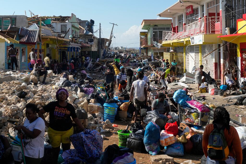 Residentes, entre los escombros causados por el paso del huracán Melissa por una calle de Black River, Jamaica, el 30 de octubre de 2025. (AP Foto/Matías Delacroix)