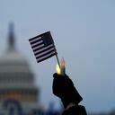 Con el edificio del Capitolio de los Estados Unidos al fondo, una persona sostiene una bandera estadounidense y velas sin llama durante una vigilia el jueves 6 de enero de 2022 en Washington, en el primer aniversario del ataque al Capitolio de los Estados Unidos. Foto AP / Julio Cortez