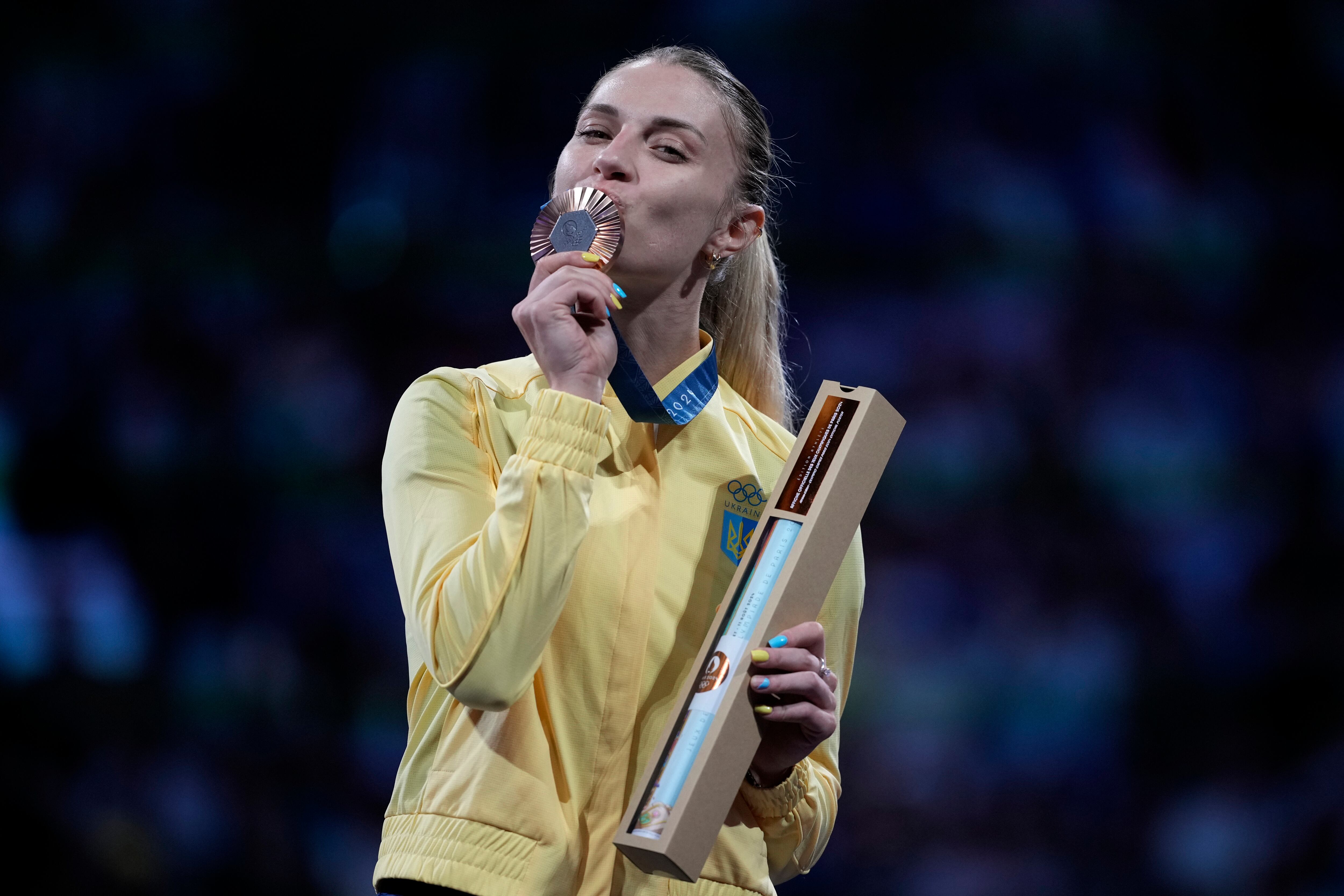 Ukraine's Olga Kharlan celebrates on the podium after winning the bronze medal in the women's individual Sabre competition during the 2024 Summer Olympics at the Grand Palais, Monday, July 29, 2024, in Paris, France. (AP Photo/Andrew Medichini)