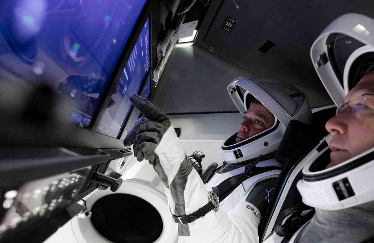 Los astronautas Doug Hurley, en primer plano, y Bob Behnken trabajan en el simulador de vuelo de SpaceX en el Centro Espacial Kennedy en Cabo Cañaveral, Florida, mientras los equipos de SpaceX en Firing Room 4 en Kennedy Space Center y Mission Control de la compañía en Hawthorne, California, junto con los controladores de vuelo de la NASA en Mission Control Houston, realizan una simulación completa de lanzamiento y atraque de la nave espacial Crew Dragon. Foto: SpaceX a través de AP