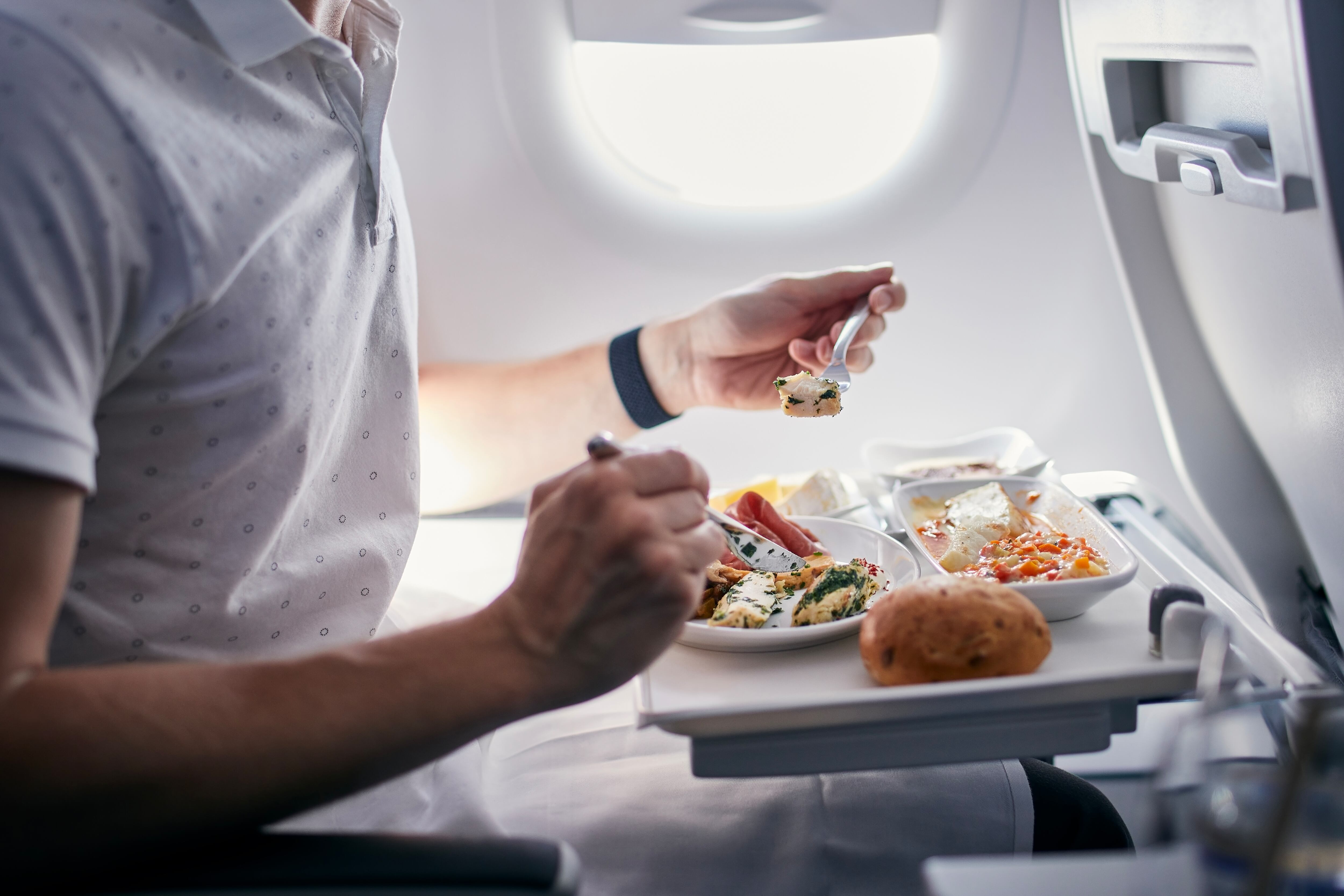 Pasajero comiendo comida de avión. Imagen de referencia