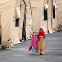 Dos niños caminan junto a las carpas en la base aérea de Ramstein U.S. en Ramstein, Alemania, lunes, 30 de agosto de 2021. La comunidad militar estadounidense más grande en el extranjero alberga miles de evacuados afganos en una ciudad de TENT en la barra aérea. (AP Foto / Matthias Schrader)
