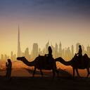Turistas en camellos contemplando Dubái, unos de los uno de los siete emiratos que conforman los Emiratos Árabes Unidos