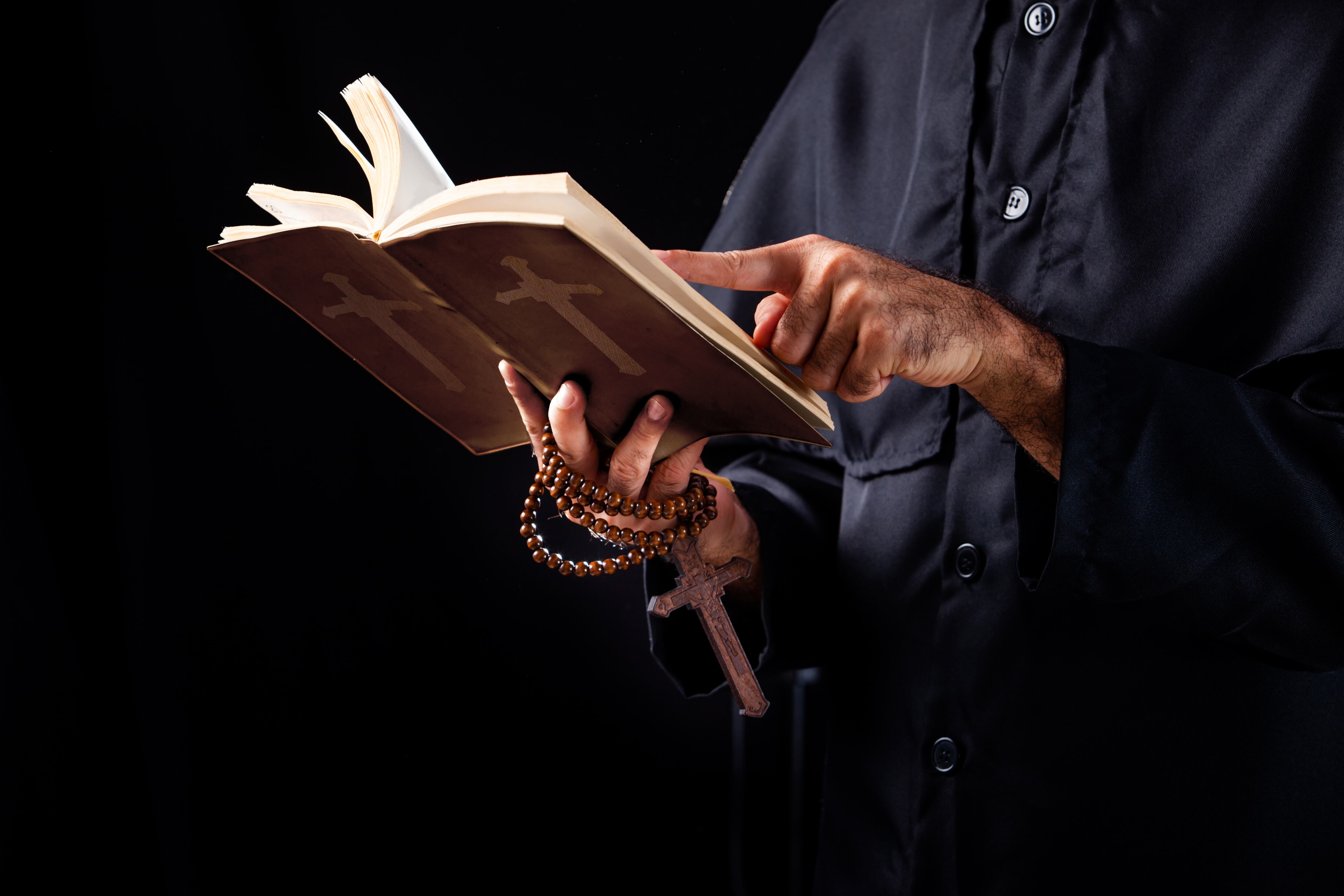 Pastor cristiano reads the Bible.The cross in the Pastor hand