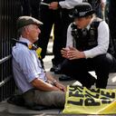 La policía habla con un manifestante de Extinction Rebellion que se ha encadenado a las rejas del Palacio de Westminster antes de su arresto, mientras que el grupo dice que otros manifestantes se han amarrado con una cadena alrededor de la silla del orador dentro de la Cámara de los Comunes en Londres. Viernes, 2 de septiembre de 2022. Foto AP/Frank Augstein