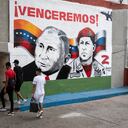 Jóvenes caminan frente a un mural pintado por la brigada muralista zapatista de la comunidad de La Piedrita y que representa al presidente ruso Vladimir Putin junto al difunto presidente venezolano Hugo Chávez. (Photo by Yuri CORTEZ / AFP)