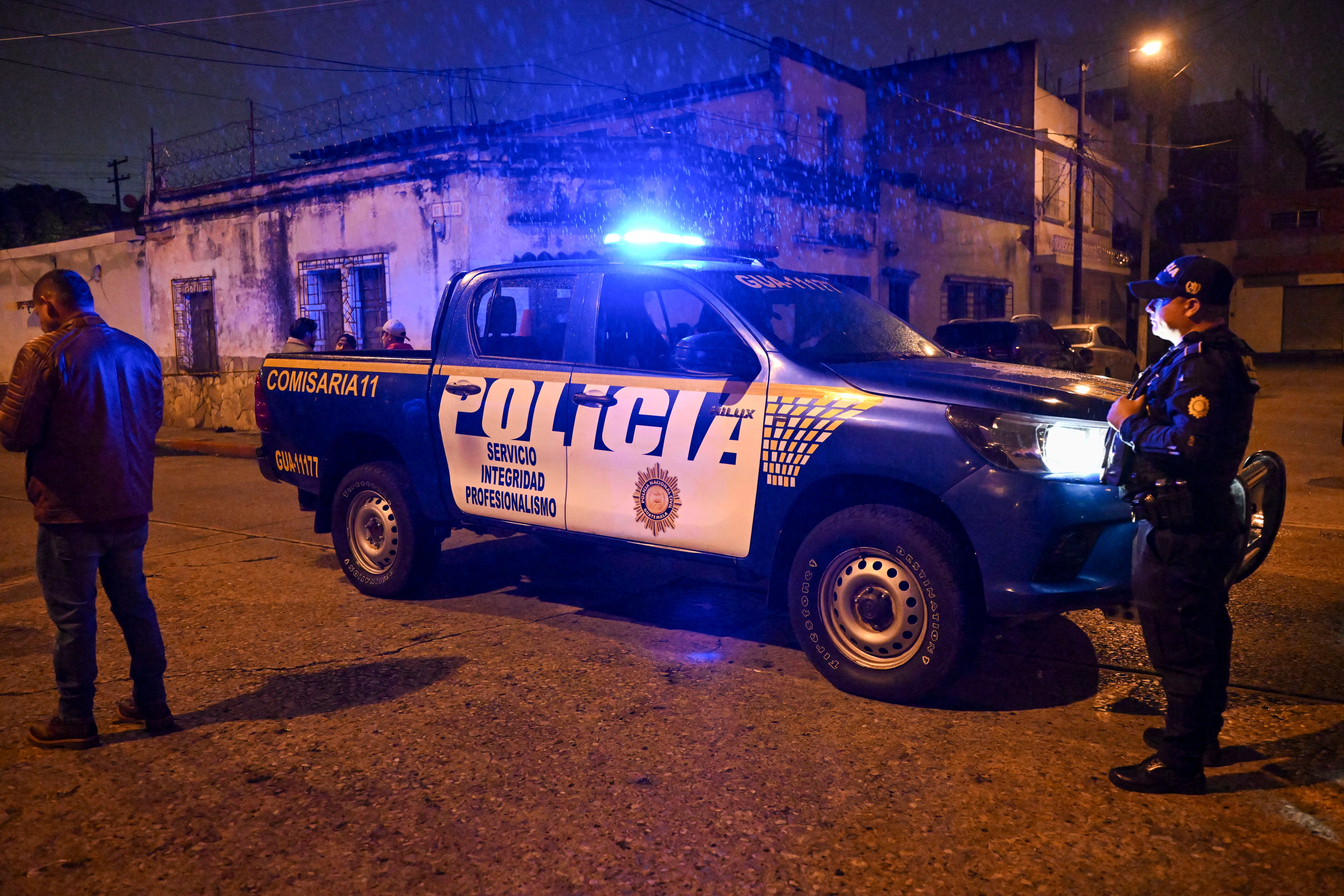 Un policía junto a miembros del Ministerio Público busca evidencias junto a la escena de un crimen donde siete personas fueron asesinadas en un ataque perpetrado por presuntos pandilleros en una funeraria en la Ciudad de Guatemala el 30 de julio de 2025. Al menos siete personas murieron y 13 resultaron heridas en un ataque armado en un funeral en la Ciudad de Guatemala, en un incidente que las autoridades vincularon con disputas entre pandillas, informaron las autoridades. (Foto de JOHAN ORDONEZ / AFP)