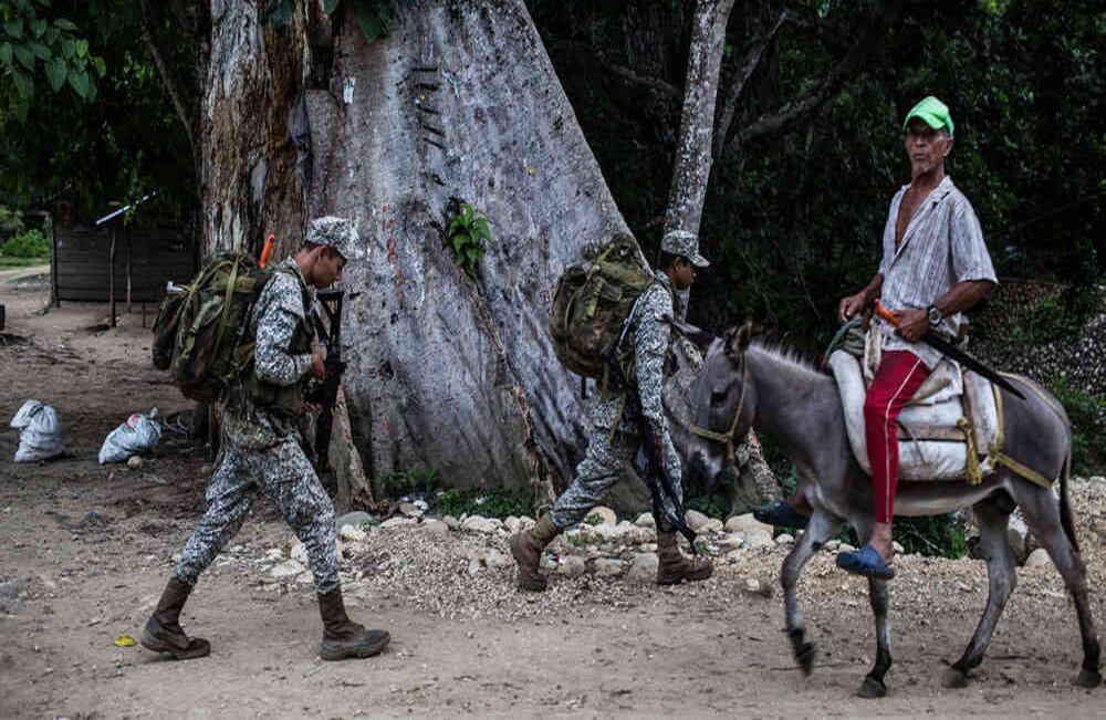 En la entrada de Macayepo hombres de la Infantería de la Armada pasan por un árbol donde los pobladores cuentan, eran ejecutadas por combatientes de la guerrilla de las FARC personas, acusadas de ser auxiliadores de los paramilitares. Mauricio Morales.