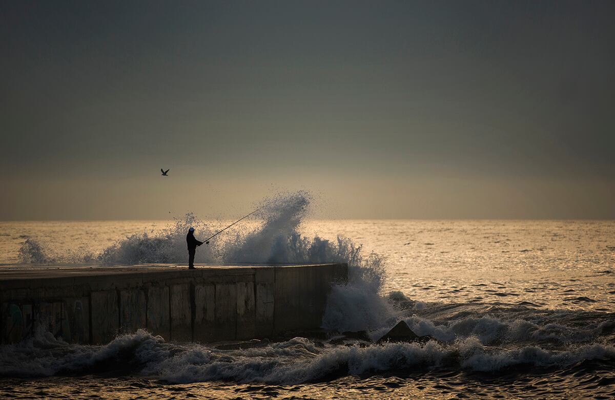 Un hombre pesca en el Mar Mediterráneo desde un muelle en Barcelona, España. (AP)