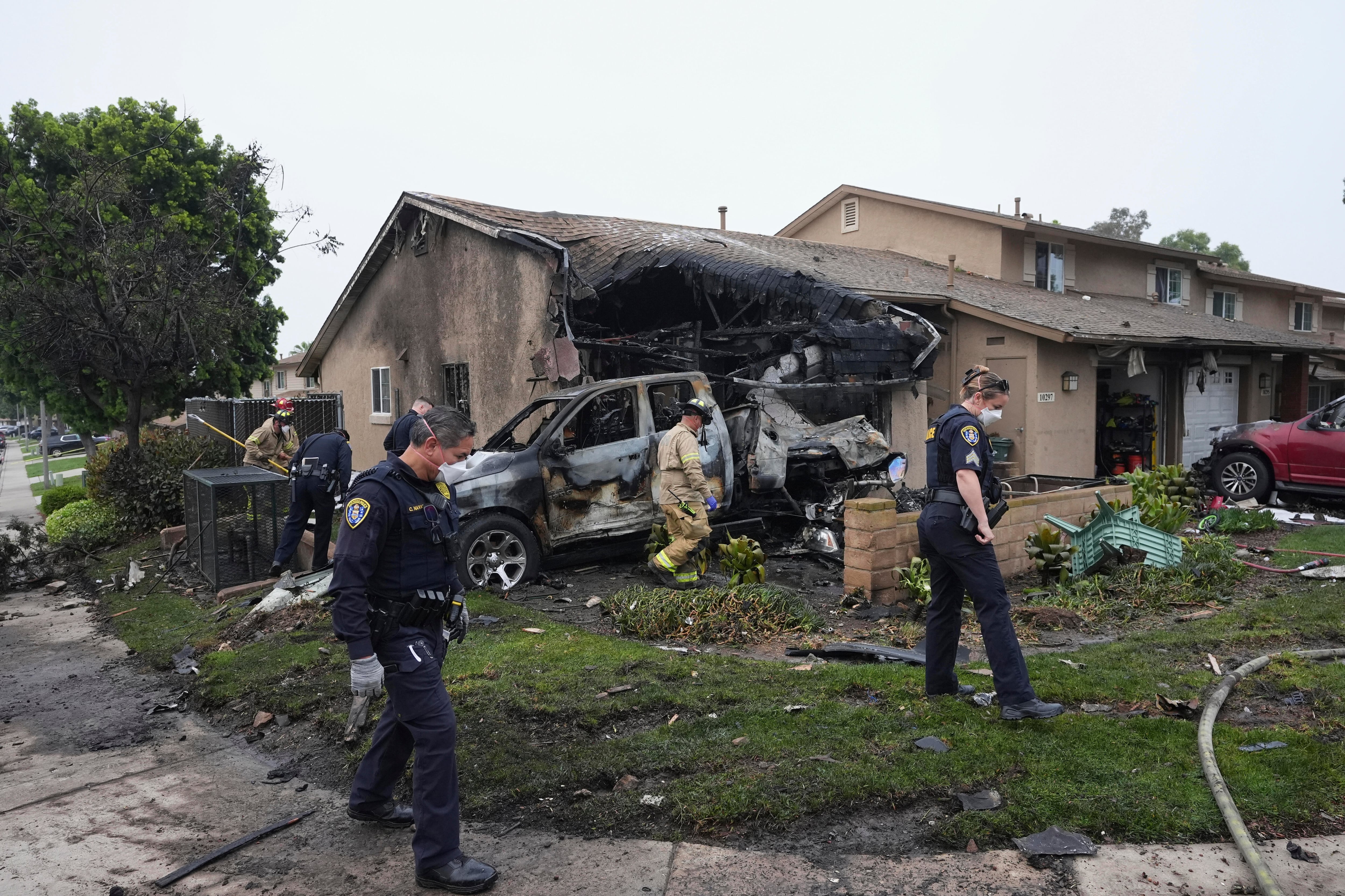 Authorities work the scene where a small plane crashed into a San Diego neighborhood, setting several homes on fire and forcing evacuations along several blocks early Thursday, May 22, 2025. (AP Photo/Gregory Bull)