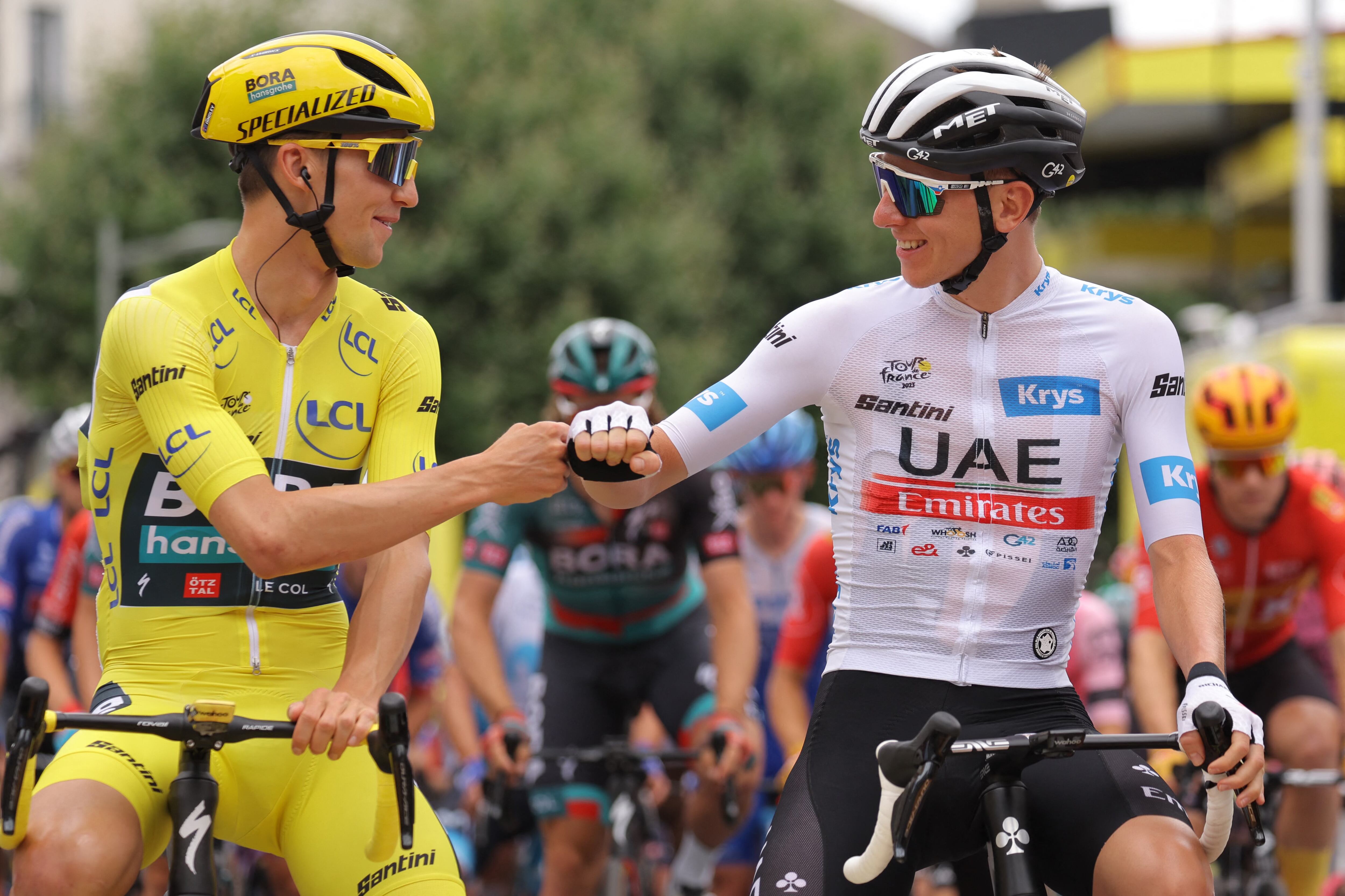 BORA - hansgrohe's Australian rider Jai Hindley wearing the overall leader's yellow jersey (L) bumps fists with UAE Team Emirates' Slovenian rider Tadej Pogacar wearing the best young rider's white jersey (R) as they await the start of the 6th stage of the 110th edition of the Tour de France cycling race, 145 km between Tarbes and Cauterets-Cambasque, in the Pyrenees mountains in southwestern France, on July 6, 2023. (Photo by Thomas SAMSON / AFP)