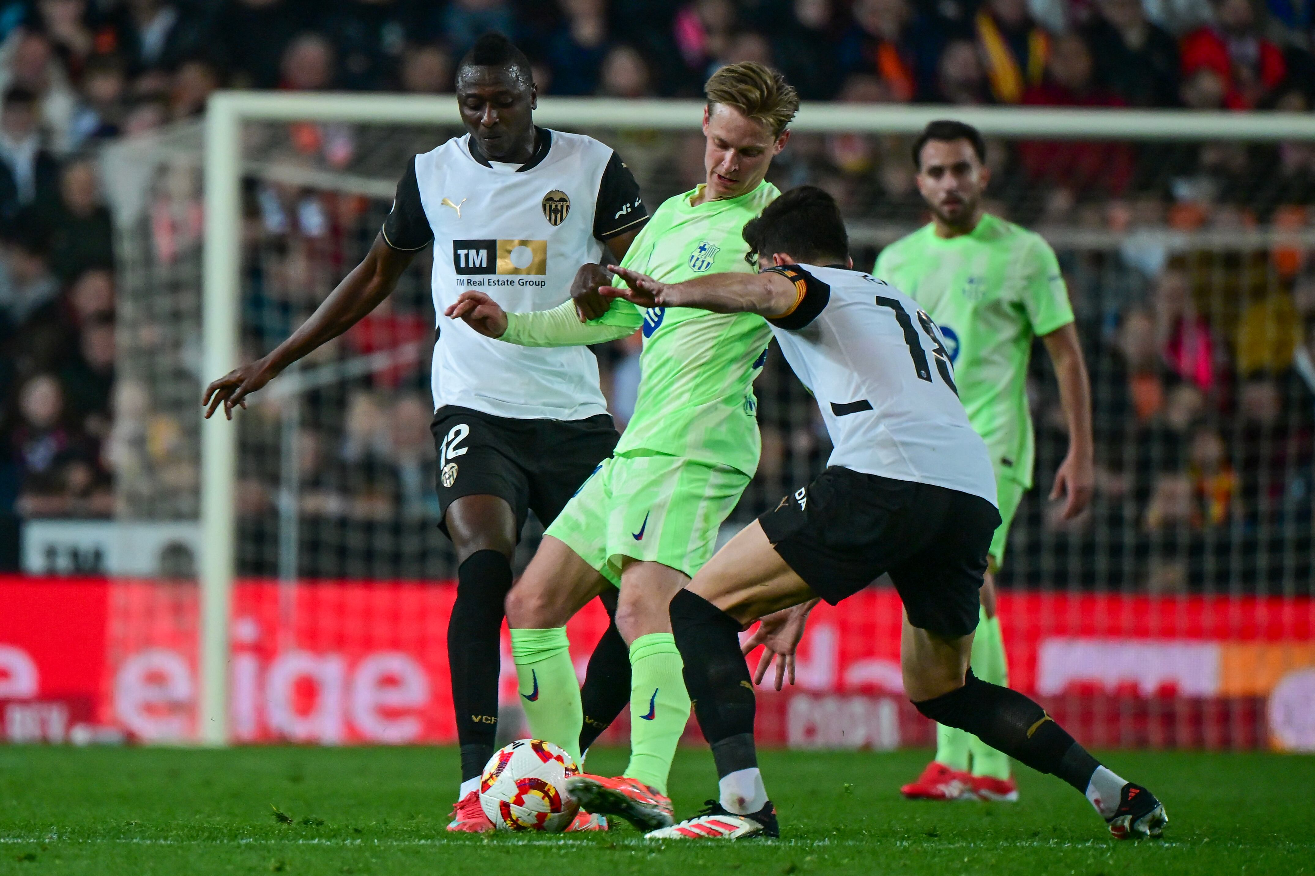Barcelona's Dutch midfielder #21 Frenkie De Jong (C) is challenged by Valencia's Spanish midfielder #18 Jose Luis Garcia Vaya 'Pepelu' (R) and Valencia's Nigerian forward #12 Sadiq Umar during the Spanish Copa del Rey (King's Cup) quarter-final first leg football match between Valencia CF and FC Barcelona at Mestalla Stadium in Valencia on February 6, 2025. (Photo by JOSE JORDAN / AFP)