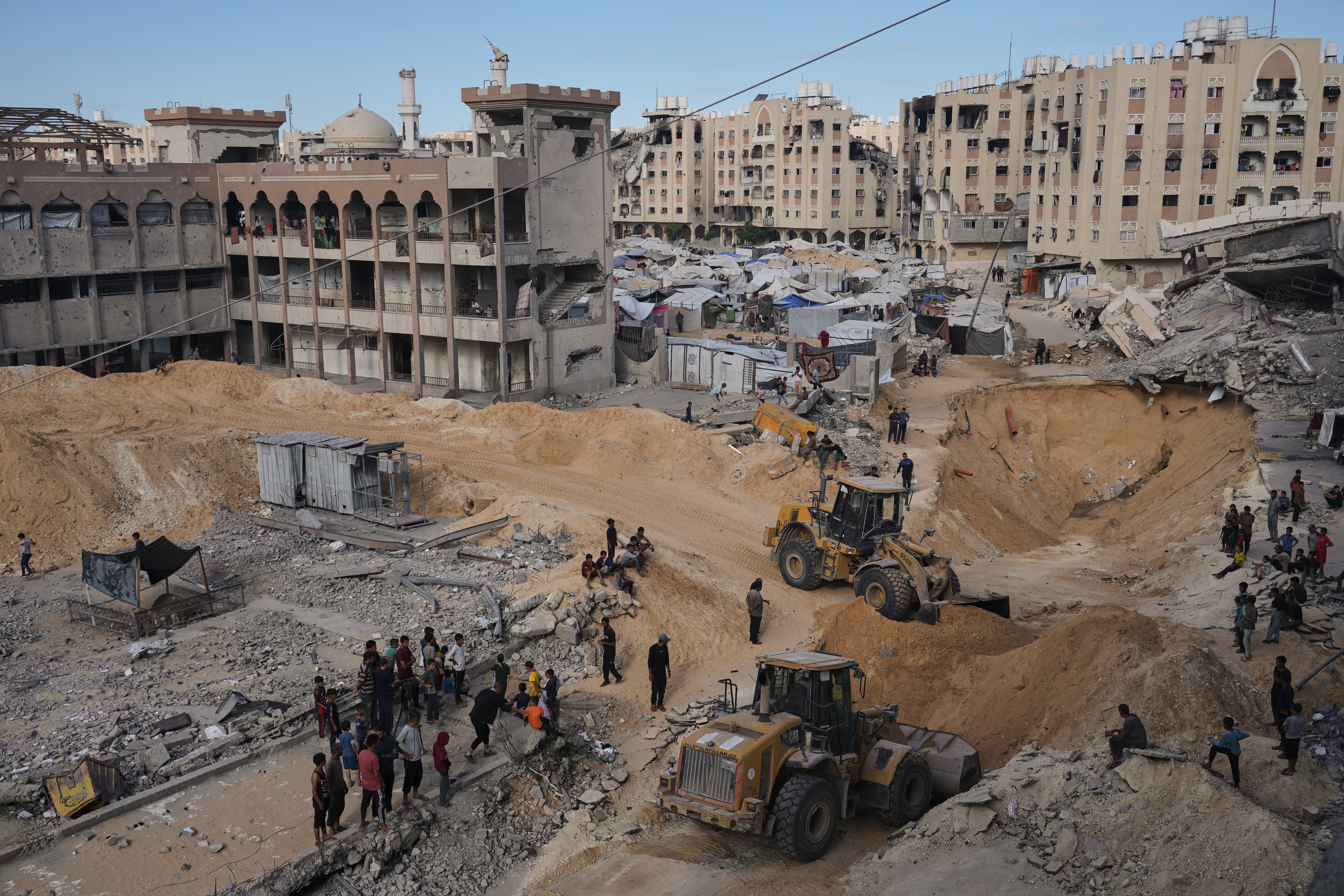 Palestinos observan a miembros del grupo militante Hamás buscando los cuerpos de los rehenes en una zona de la ciudad de Hamad, Khan Younis, en el sur de la Franja de Gaza