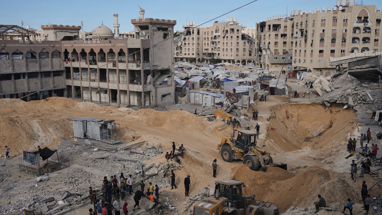 Palestinos observan a miembros del grupo militante Hamás buscando los cuerpos de los rehenes en una zona de la ciudad de Hamad, Khan Younis, en el sur de la Franja de Gaza.