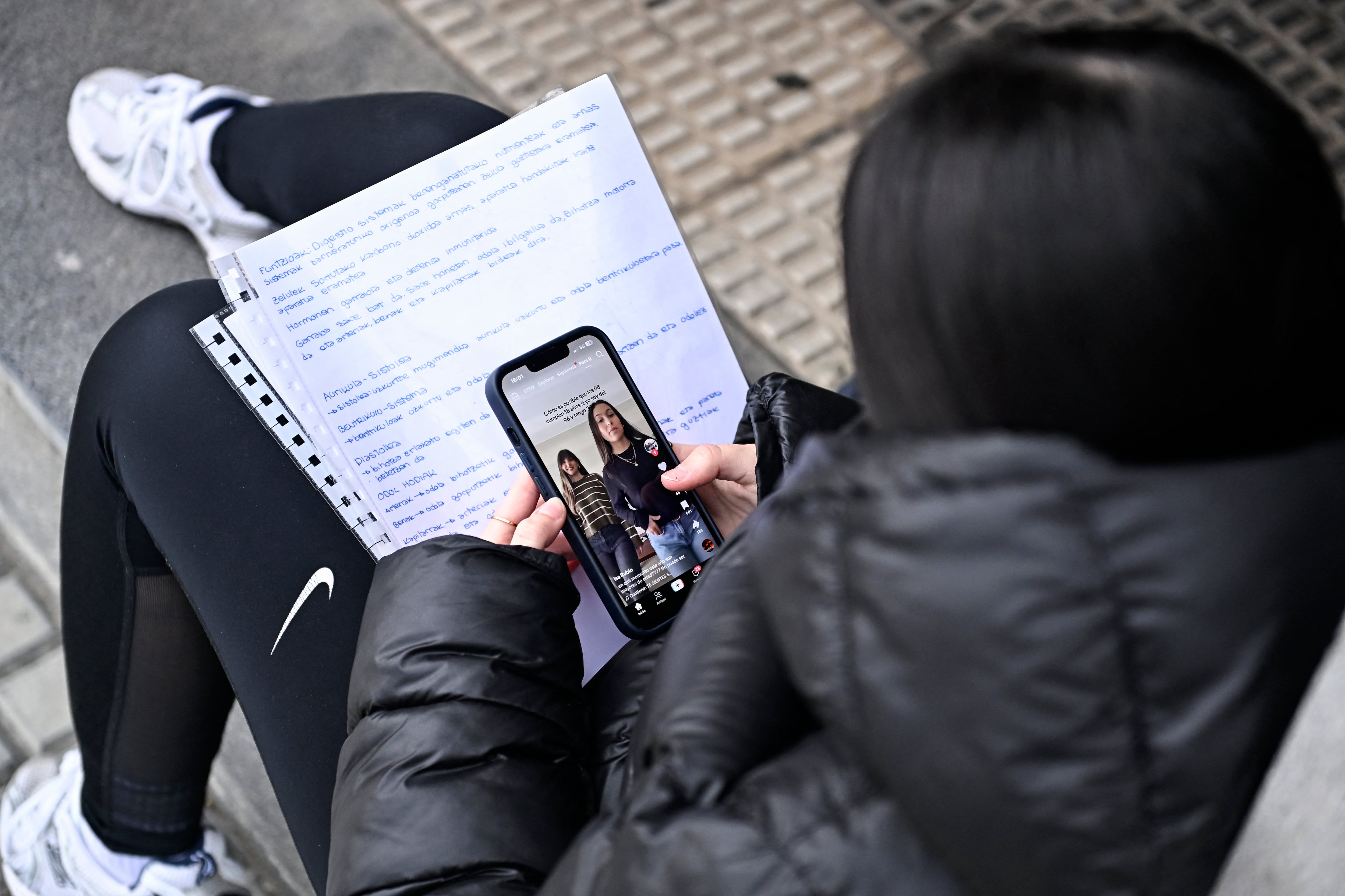 A teenager scrolls through social media on her phone in the Spanish Basque city of San Sebastian on February 4, 2026. Spain will seek to ban social media for under-16s to protect them from harmful content such as pornography and violence, Prime Minister Pedro Sanchez said yesterday, drawing a furious response from X owner Elon Musk. Telegram founder Pavel Durov today joined fellow tech tycoon Elon Musk in slamming Spanish Prime Minister Pedro Sanchez over his "dangerous" plan to ban social media for under-16s. (Photo by ANDER GILLENEA / AFP)