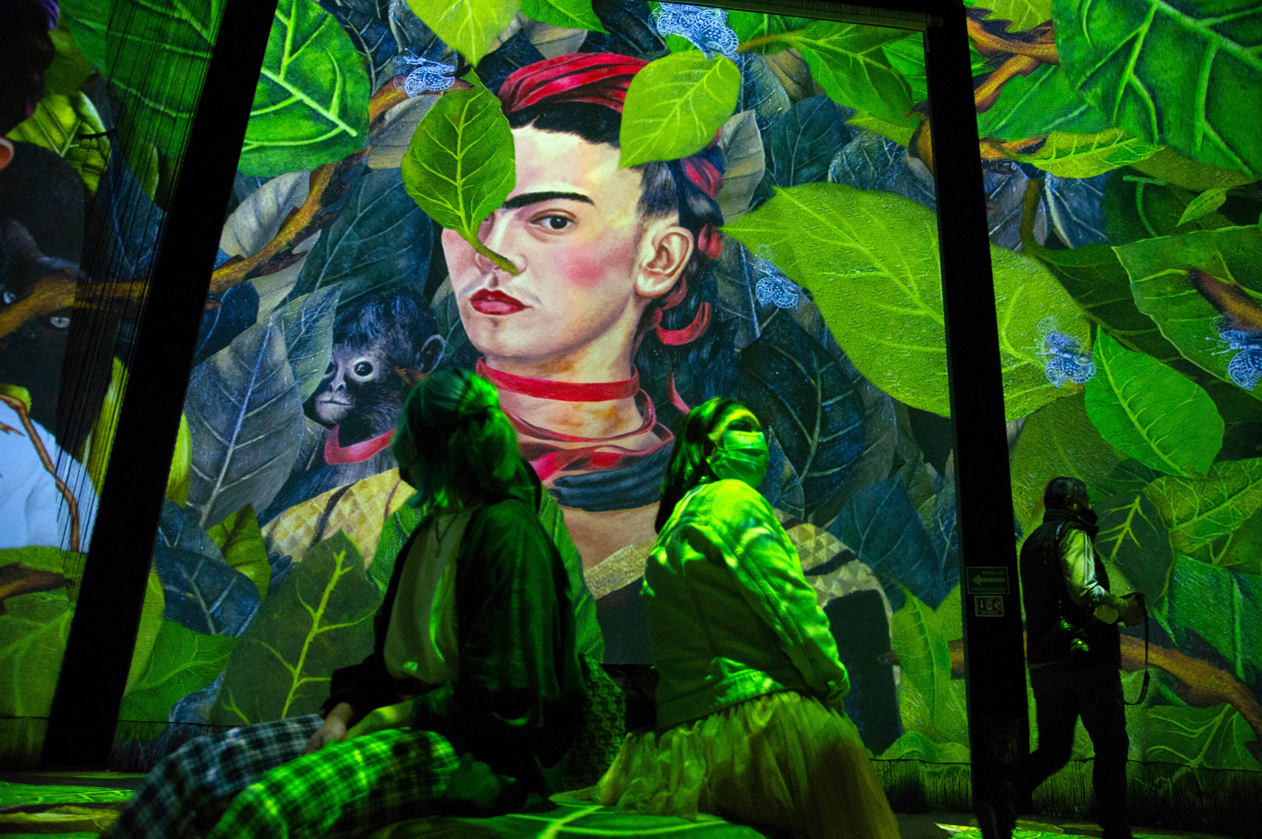 People attend the inauguration of the exhibition "Frida, the immersive experience" in Mexico City on July 6, 2021. - Images of the most famous paintings of iconic Mexican artist Frida Kahlo (1907-1954) are projected on enormous screens and curtains as traditional music plays, as part of a digital exposition that celebrates her life and work, which was premiered on the 114th anniversary of her birth. (Photo by CLAUDIO CRUZ / AFP) / RESTRICTED TO EDITORIAL USE - MANDATORY MENTION OF THE ARTIST UPON PUBLICATION - TO ILLUSTRATE THE EVENT AS SPECIFIED IN THE CAPTION
