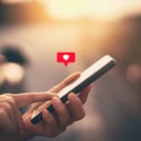 Close up woman hand hold using smart phone with heart icon at outdoor park street background. Copy space of technology business and travel holiday concept. Vintage tone filter effect color style.