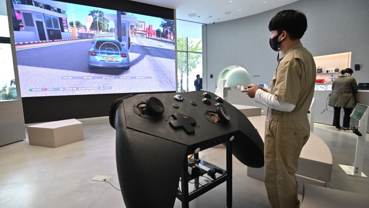 Una persona juega junto a un control gigante de videojuegos y un televisor, en Seúl (Photo by Jung Yeon-je / AFP)