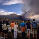Los turistas miran y toman fotos de un volcán mientras continúa en erupción en la isla canaria de La Palma, España, el martes 26 de octubre de 2021. (AP Photo/Emilio Morenatti)