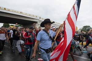 Roberto Márquez, un pintor mexicano que vive entre México y EE. UU., lleva una bandera de EE. UU. y tira de su equipaje cuando se une a una caravana de migrantes que sale de la ciudad de Tapachula, en el estado de Chiapas, México.