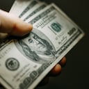 Mano de hombre con una pila de billetes de cien dólares estadounidenses, de cerca