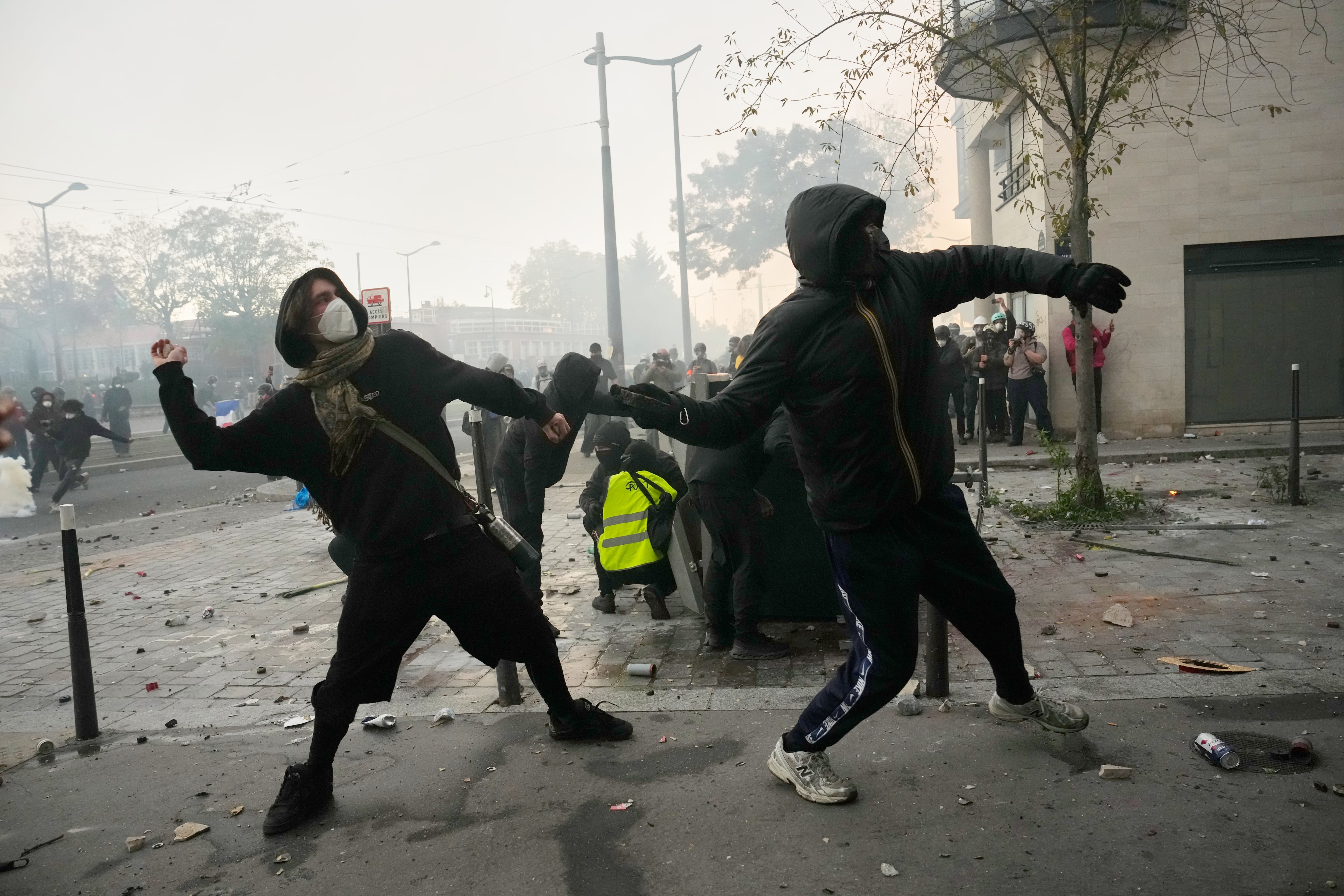 Manifestantes lanzan piedras durante protestas por el costo de vida y la educación en París, Francia.