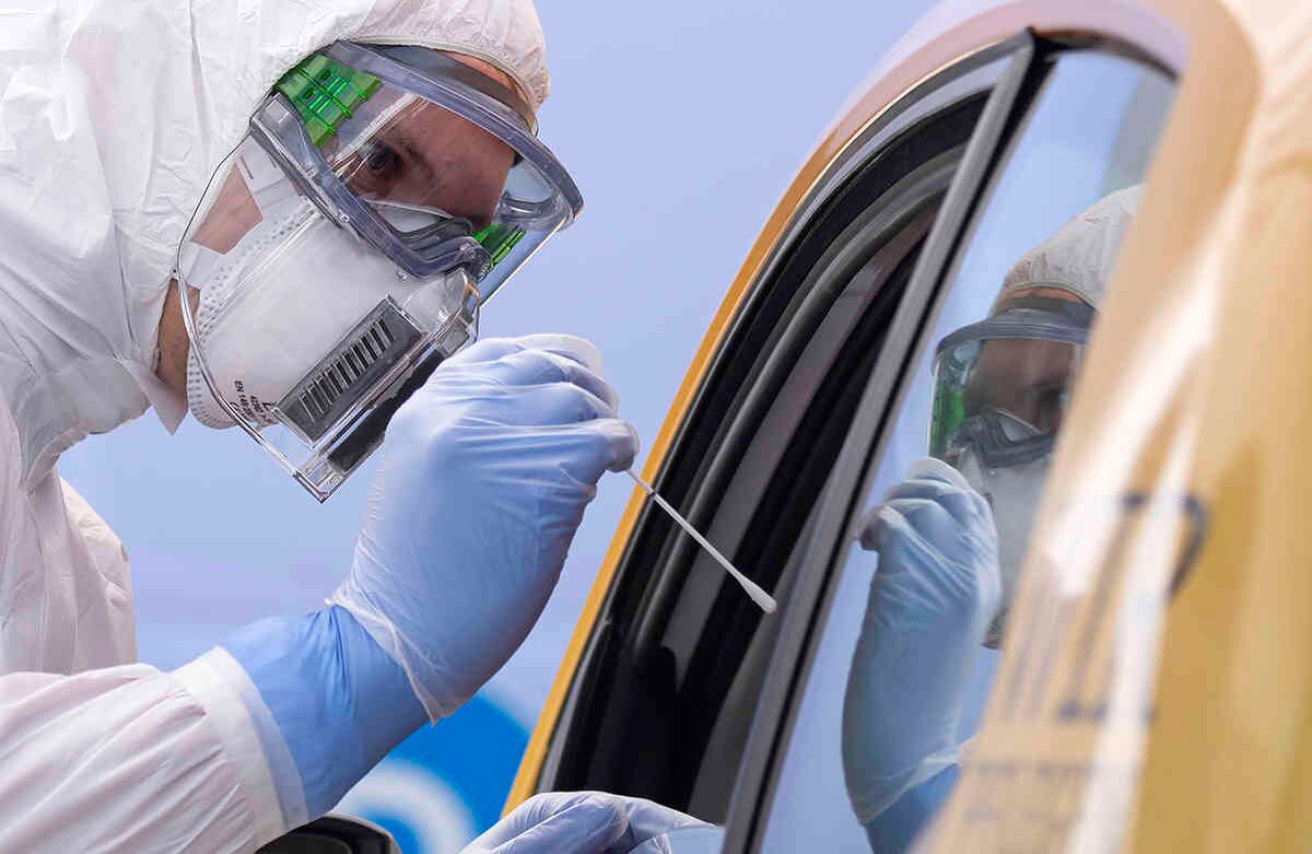 Un ayudante de la Cruz Roja Alemana DRK en traje de protección, a la izquierda, toma un frotis de un paciente en su coche, durante la apertura oficial de un centro de pruebas del covid-19, en el recinto ferial en Dresden, Alemania, el 15 de abril. En Alemania, la epidemia se ha vuelto controlable, según el gobierno. Foto: Jens Meyer/ AP 