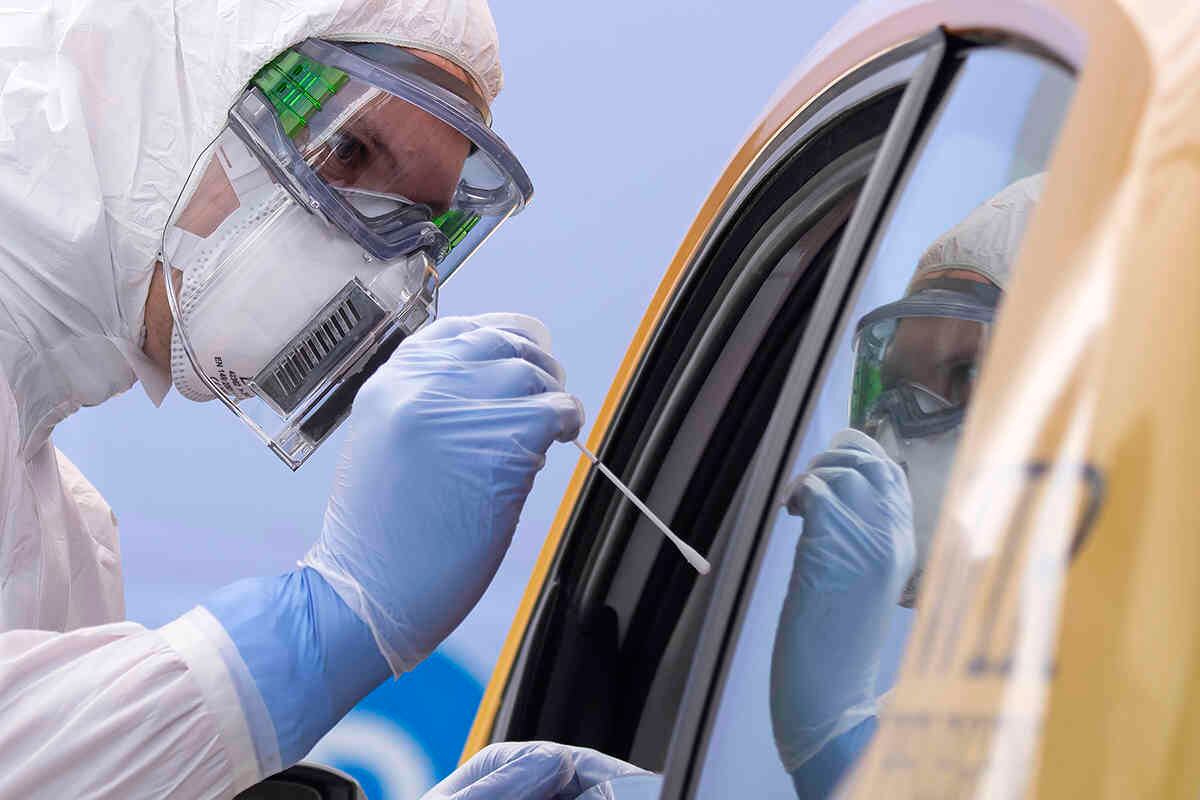Un ayudante de la Cruz Roja Alemana DRK en traje de protección, a la izquierda, toma un frotis de un paciente en su coche, durante la apertura oficial de un centro de pruebas del covid-19, en el recinto ferial en Dresden, Alemania. Foto: Jens Meyer/ AP 