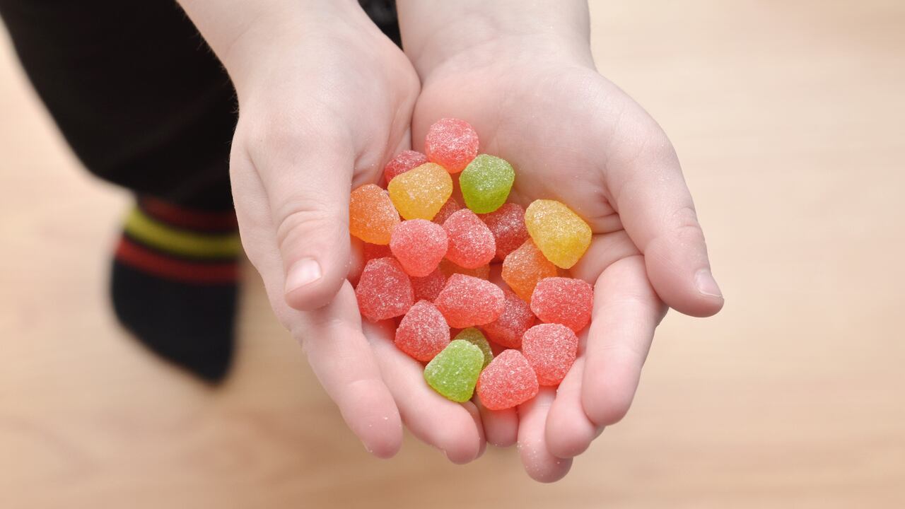 Close up of a young boy holding candy gum drops in his hands.
