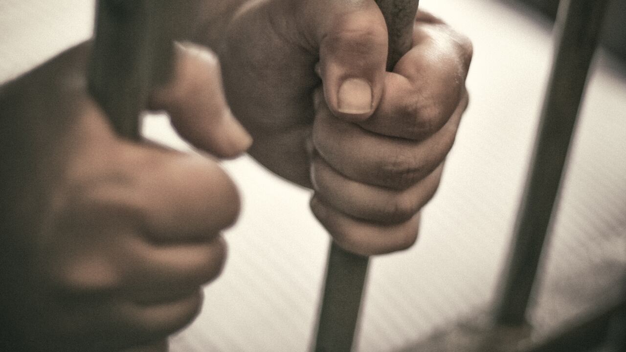 Las manos del hombre sujetan con fuerza los barrotes de su celda.