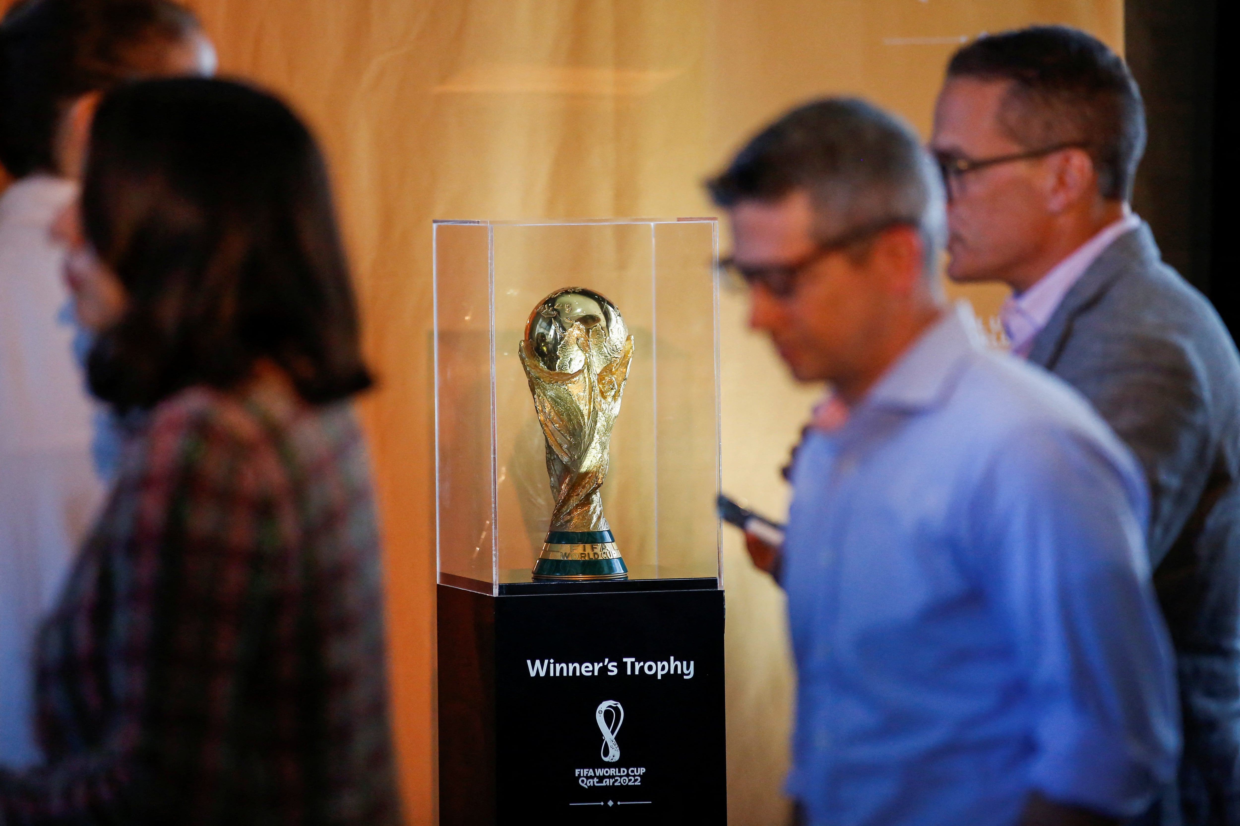 People walk next to the Official FIFA World Cup Trophy as it is displayed during the FIFA/Frito Lay news conference ahead of 2026 World Cup while in New York City, New York, U.S., June 17, 2022.  REUTERS/Eduardo Munoz