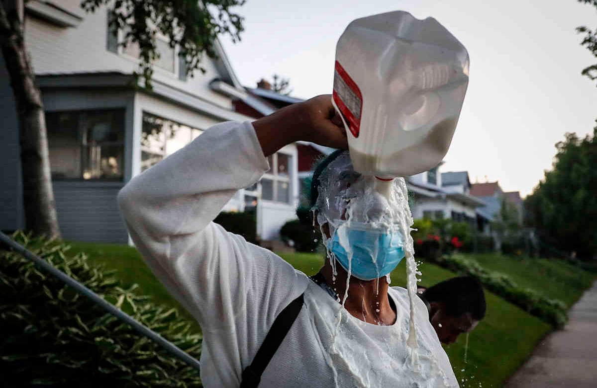 Un manifestante empapa su cara con leche después de haber sido expuesta a gases lacrimógenos disparados por la policía, el jueves 28 de mayo de 2020, en St. Paul, Minnesota. (Foto AP / John Minchillo)