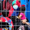 Una persona con un niño se sienta detrás de una cerca en la base aérea de Ramstein Us, en Ramstein, Alemania, lunes, 30 de agosto, 2021. La comunidad militar estadounidense más grande en el extranjero alberga miles de evacuados afganos en una ciudad de TENT en la barra aérea. (AP Foto / Matthias Schrader)