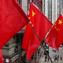 La gente camina bajo las banderas nacionales chinas colocadas en una pasarela para conmemorar el 24º aniversario de la entrega de Hong Kong a China en una escuela de Hong Kong el jueves 1 de julio de 2021. Foto: AP Photo/Vincent Yu