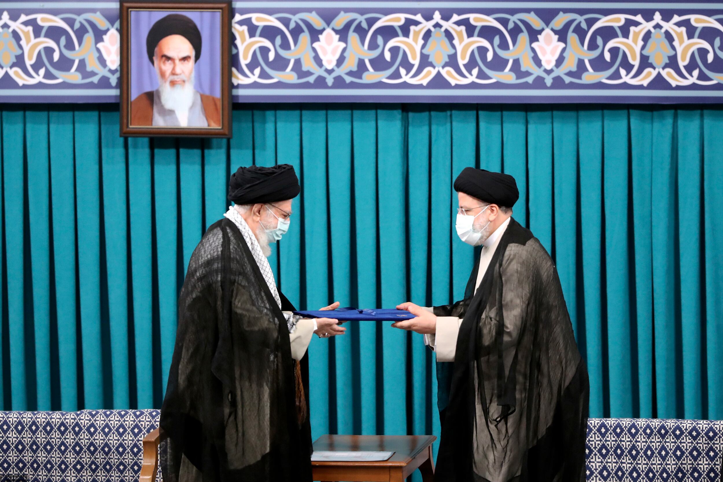 En esta foto publicada por un sitio web oficial de la oficina del líder supremo iraní, el líder supremo, el ayatolá Ali Khamenei, a la izquierda, otorga su sello oficial de aprobación al presidente recién electo Ebrahim Raisi en una ceremonia de respaldo en Teherán, Irán. (Office of the Iranian Supreme Leader via AP)