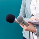 Reporter or TV journalist at news conference, holding microphone and writing notes. Getty Images