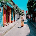 Mujer joven caminando por una calle colorida en la ciudad vieja de Cartagena, Colombia