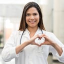 Médico cardiólogo latinoamericano en el hospital sonriendo y formando un corazón con sus manos - salud y medicina
