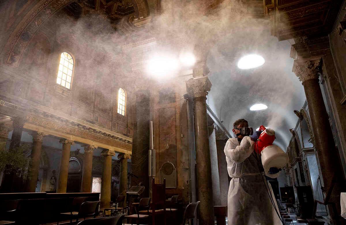 Un hombre rocía desinfectante en la Basílica del Trastevere, en Roma, el 13 de mayo. Italia levantó parcialmente el bloqueo la semana pasada, después de un cierre de dos meses. Foto: Alessandra Tarantino/ AP. 