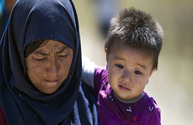 Varios refugiados esperan para cruzar la frontera entre Macedonia y Grecia, cerca del pueblo de Gevgelija, Macedonia. Las organizaciones que prestan ayuda a inmigrantes y refugiados señalan que unas 30.000 personas atraviesan la frontera a diario y que una tercera parte de ellas son mujeres y niños.