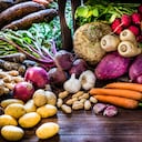 Front view of a large group of multicolored fresh organic roots, legumes and tubers shot on a rustic wooden background. The composition includes potatoes, Spanish onions, ginger, purple carrots, yucca, beetroot, garlic, peanuts, red potatoes, sweet potatoes, golden onions, turnips, parsnips, celeriac, fennels and radish. Some elements are on a rustic wooden crate. Low key DSLR photo taken with Canon EOS 6D Mark II and Canon EF 24-105 mm f/4L