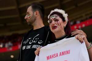 An Iran supporter, right, cries as she holds a shirt that reads 'Mahsa Amini' an Iranian woman who died while in police custody in Iran, prior to the start of the World Cup group B soccer match between Wales and Iran, at the Ahmad Bin Ali Stadium in Al Rayyan, Qatar, Friday, Nov. 25, 2022. (AP Photo/Alessandra Tarantino)