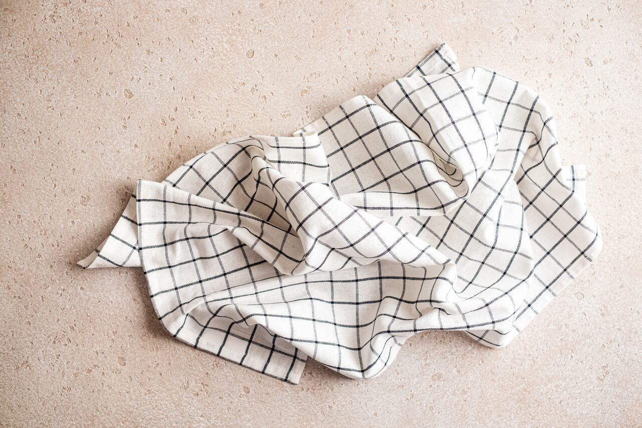 White and black linen checkered napkin folded on concrete background, top view