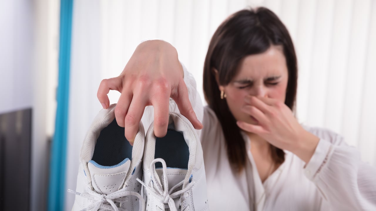 Woman Holding Dirty Smelling Shoes