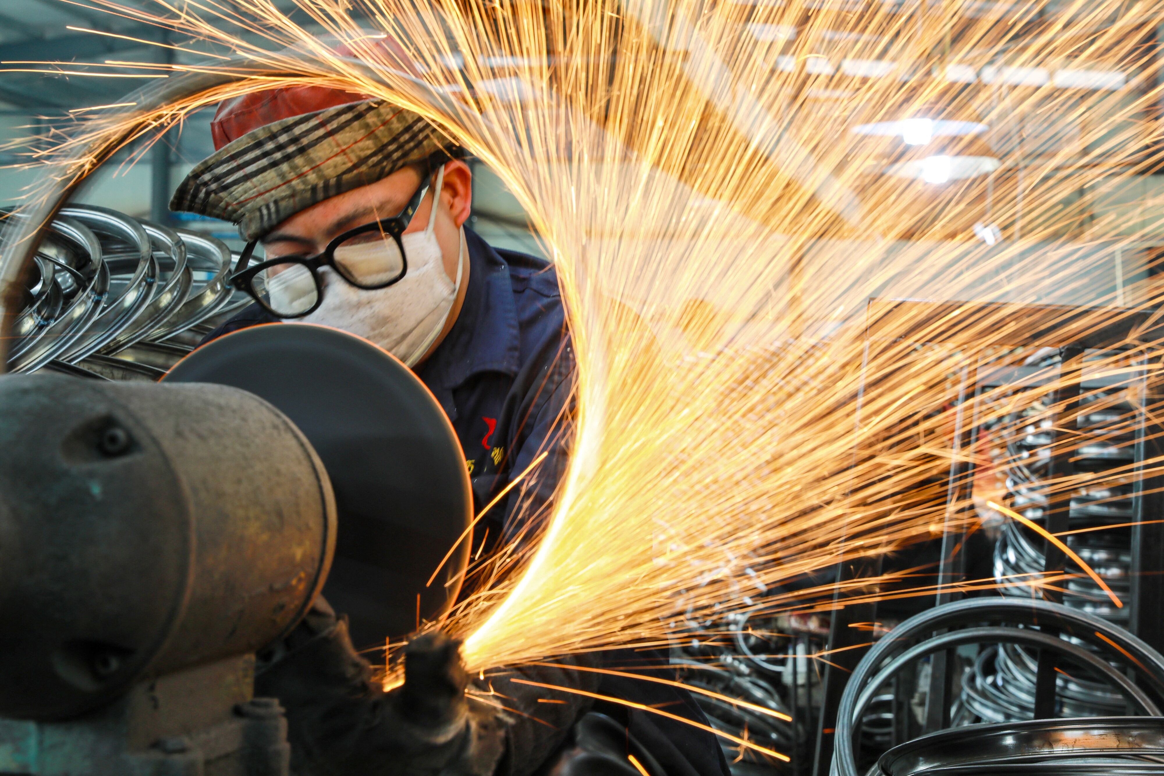 A worker welds wheels at a factory in Hangzhou in China's eastern Zhejiang province on April 16, 2021. (Photo by STR / AFP) / China OUT