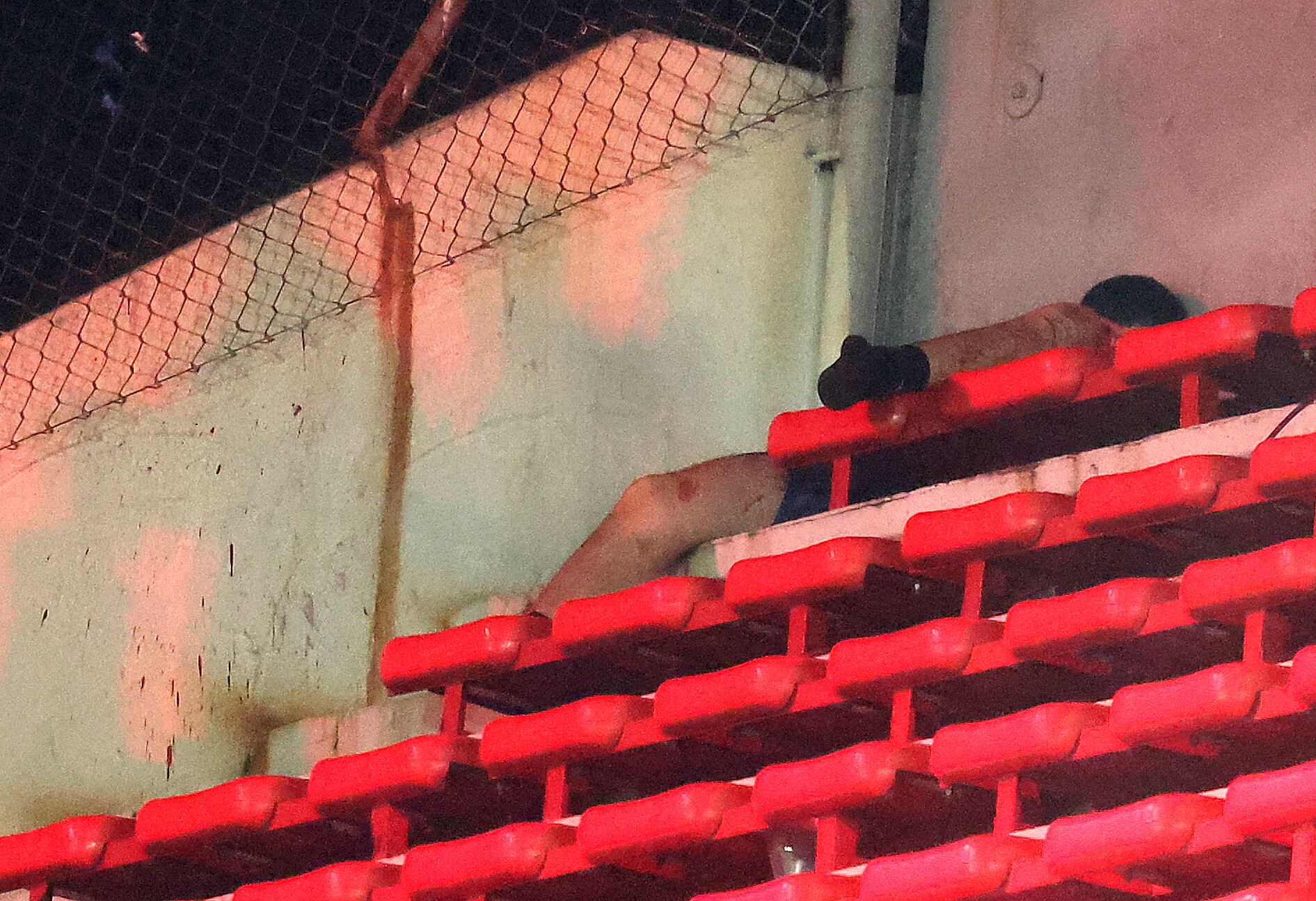 Un fanático casi desnudo de la Universidad de Chile yace herido en las gradas luego de ser golpeado por fanáticos de Independiente durante la interrupción del partido de vuelta de octavos de final de la Copa Sudamericana entre Independiente de Argentina y la Universidad de Chile de Chile en el estadio Libertadores de América en Avellaneda, provincia de Buenos Aires, Argentina, el 20 de agosto de 2025