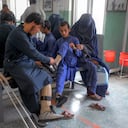 In this photograph taken on October 11, 2021, a man helps a boy put on shoes on his new prosthetic leg at the International Committee of Red Cross Rehabilitation Centre in Kabul. - Just months ago they were fighting each other as mortal enemies, but today they are amputees dealing with their new disability, together. At this Red Cross-run rehabilitation centre in Kabul, former Afghan government soldiers and Taliban fighters adjust their new prostheses, living side by side. (Photo by BULENT KILIC / AFP) / TO GO WITH: Afghanistan-conflict-health-disability, FOCUS by Emmanuel Peuchot