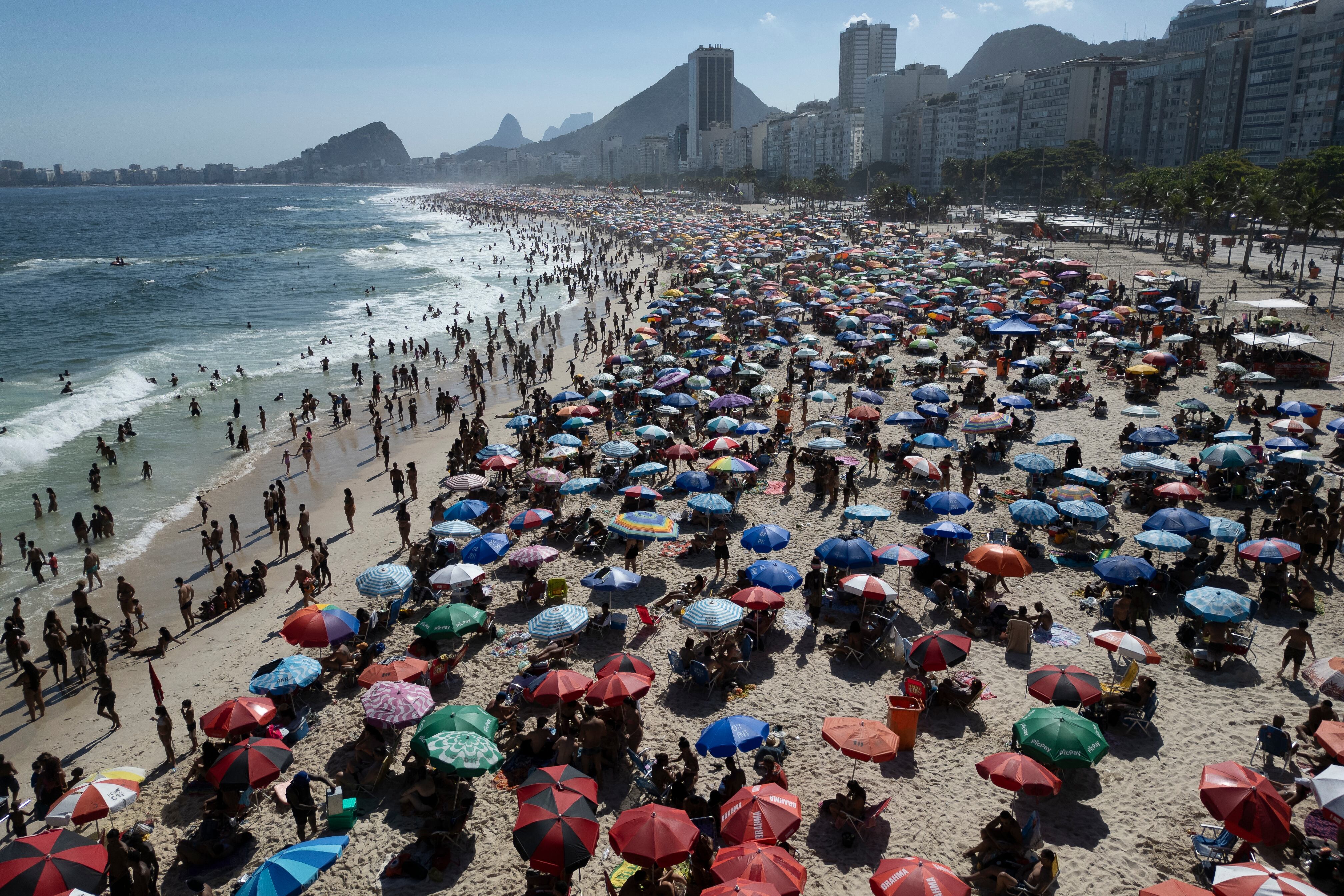 La gente disfruta del día en la playa de Copacabana en Río de Janeiro, Brasil, el 16 de febrero de 2025. (Foto de Pablo PORCIUNCULA / AFP)