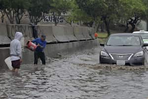 La gente intenta vaciar una calle inundada tras el paso de la tormenta tropical Hilary, que no afecta gravemente a la región a diferencia de otros lugares, en Tijuana, México, el 21 de agosto de 2023.